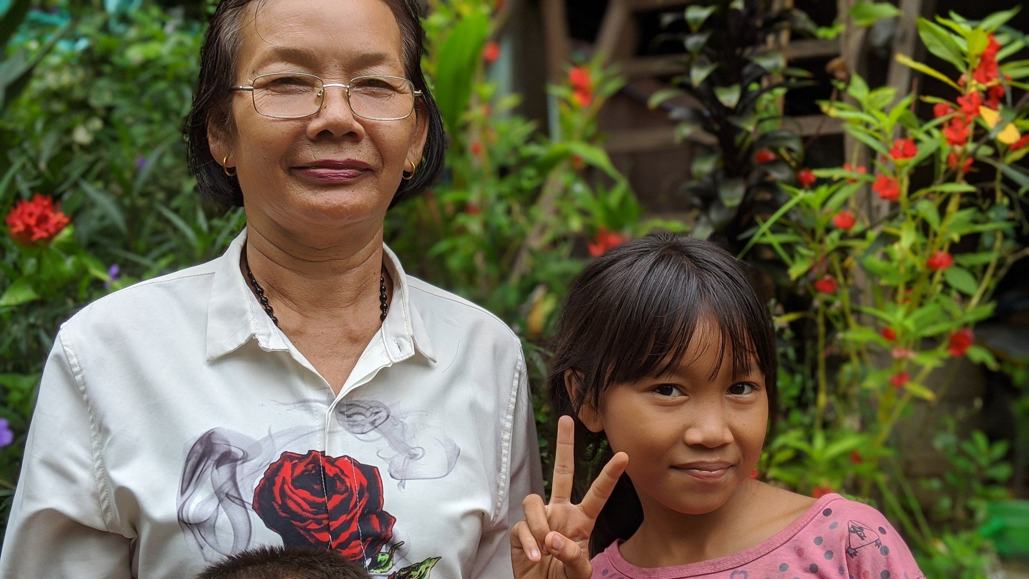 A Cambodian mother and daughter smiling together in a garden